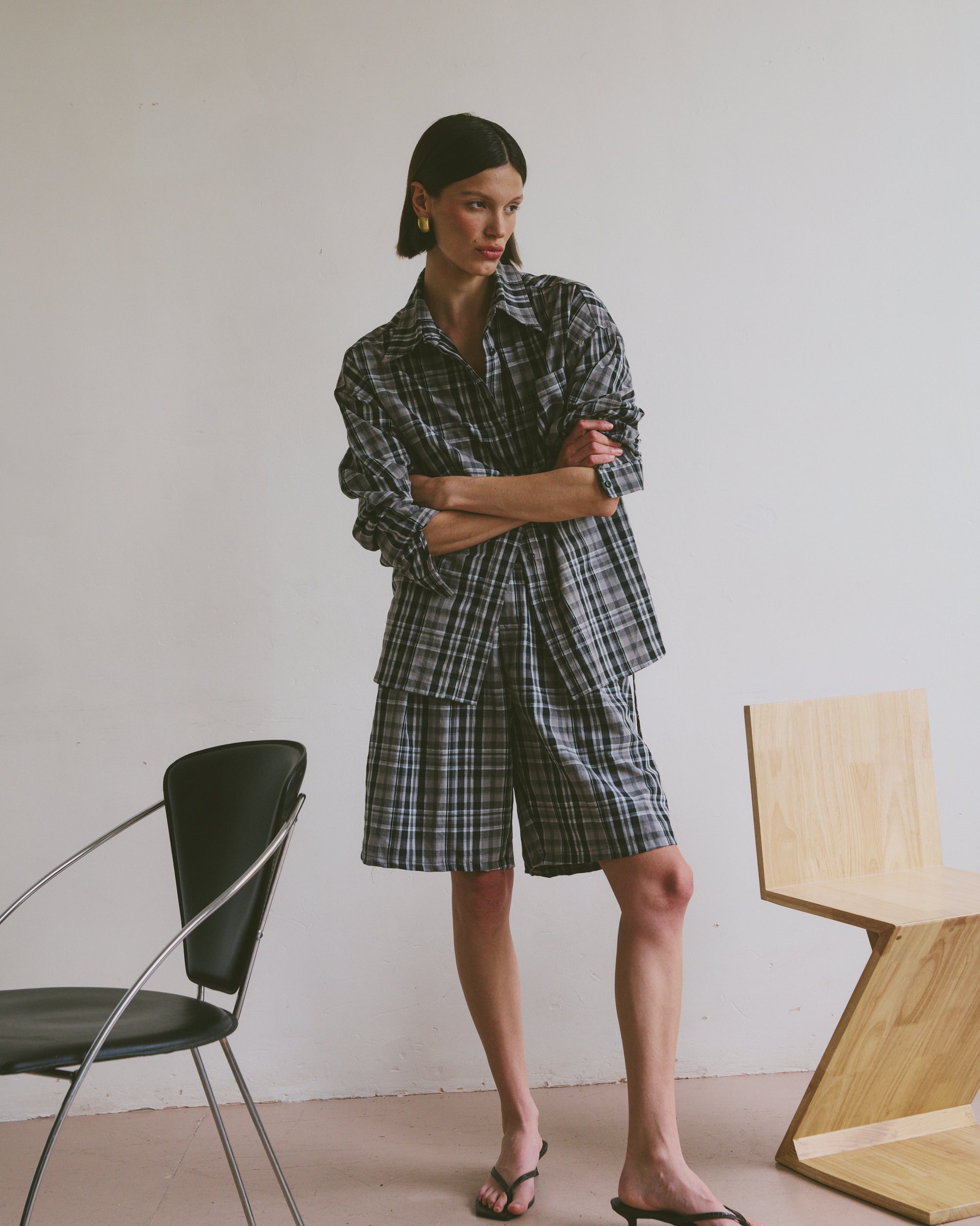 Plaid outfit standing in a minimalistic room with chairs