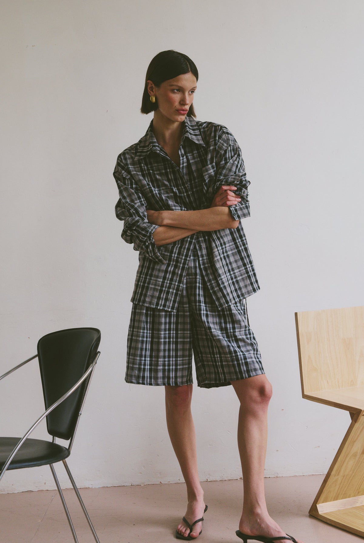 Plaid outfit standing in a minimalistic room with chairs