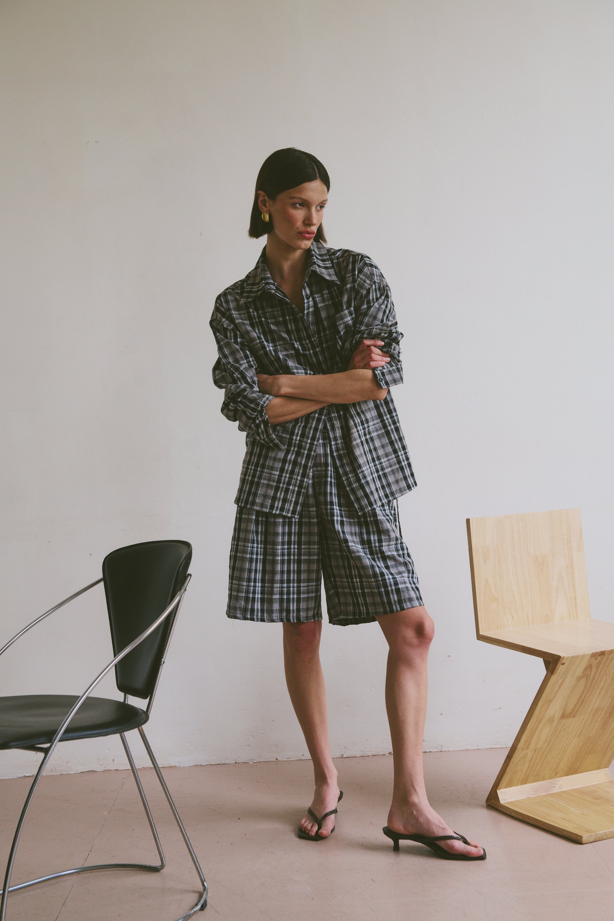 Plaid outfit standing in a minimalistic room with chairs