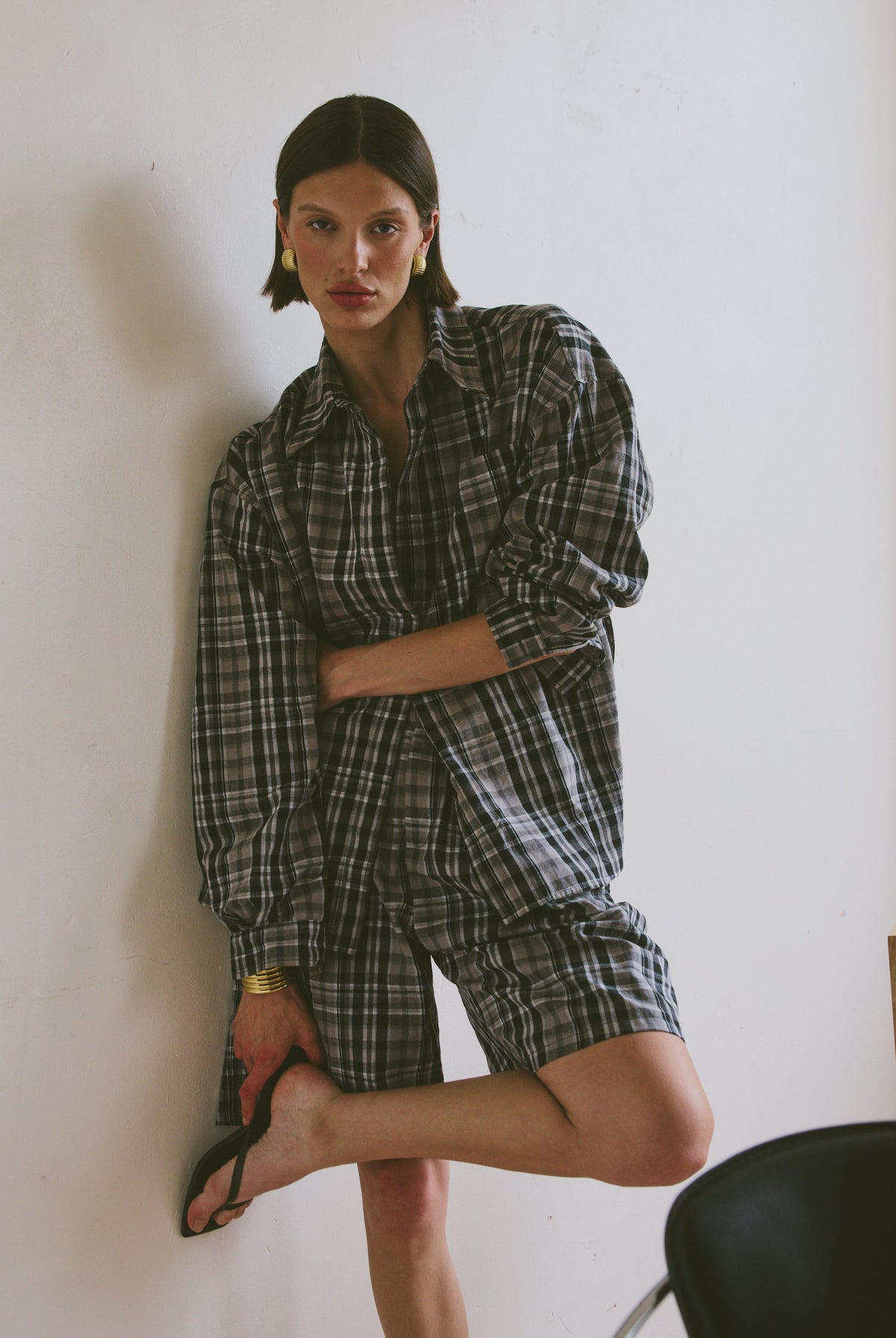 Plaid outfit standing against a white wall