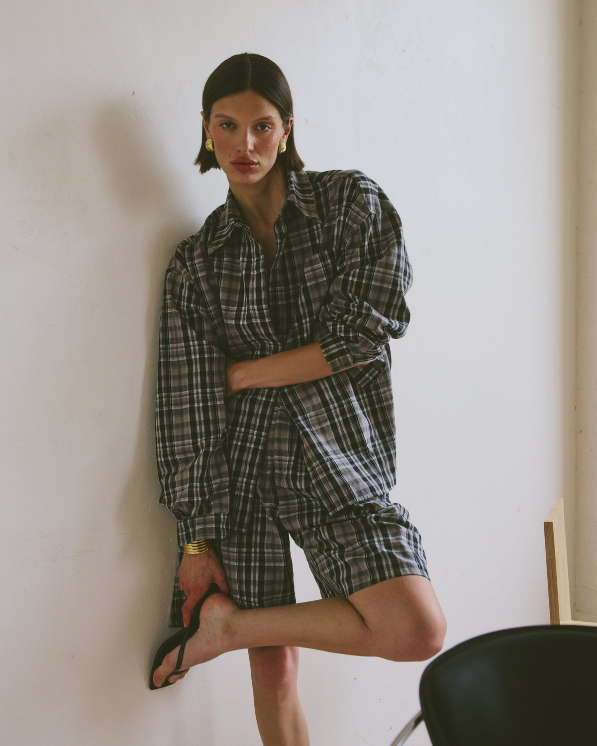 Plaid outfit standing against a white wall