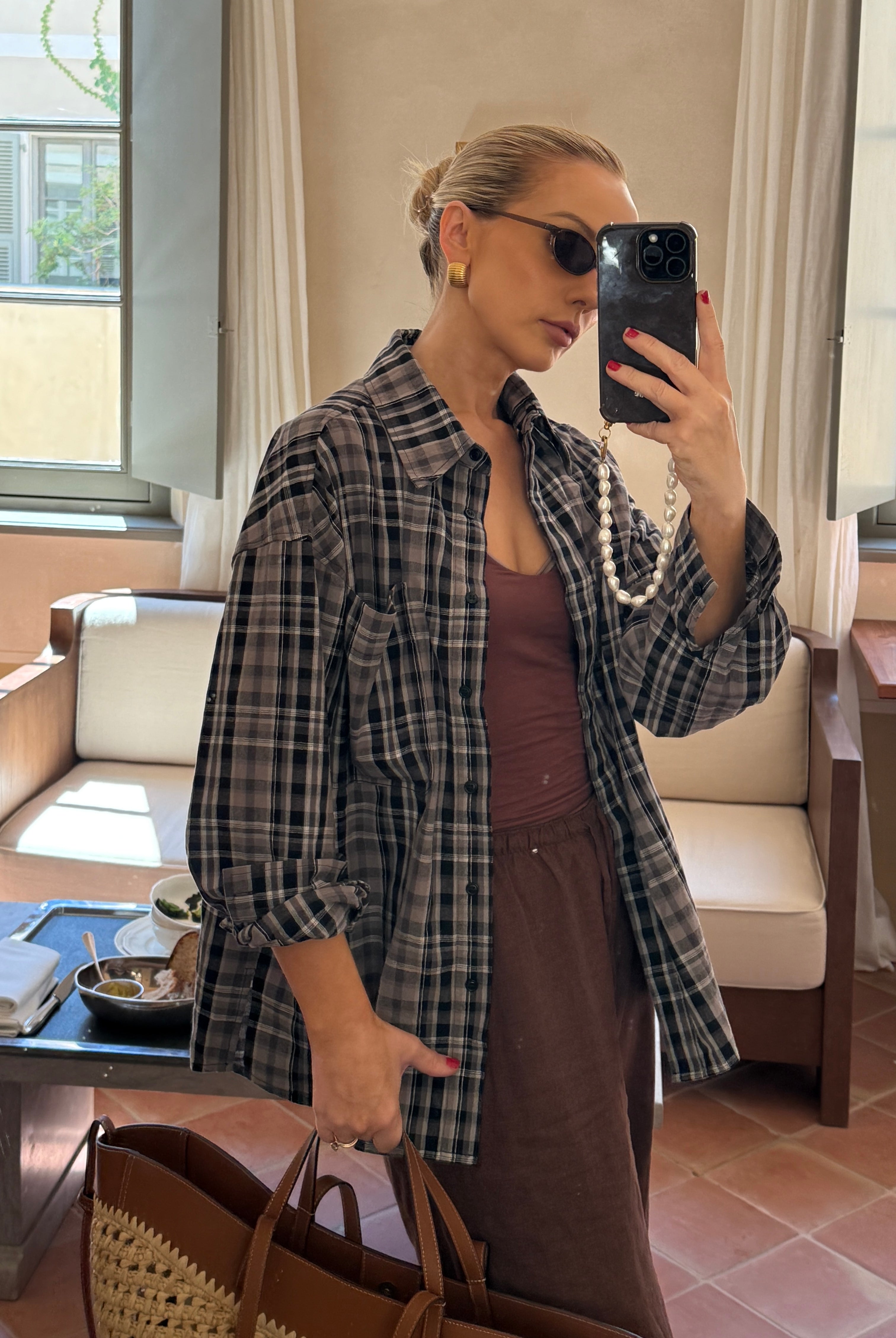 Mirror selfie in a living room, wearing a black and white relaxed plaid shirt and sunglasses