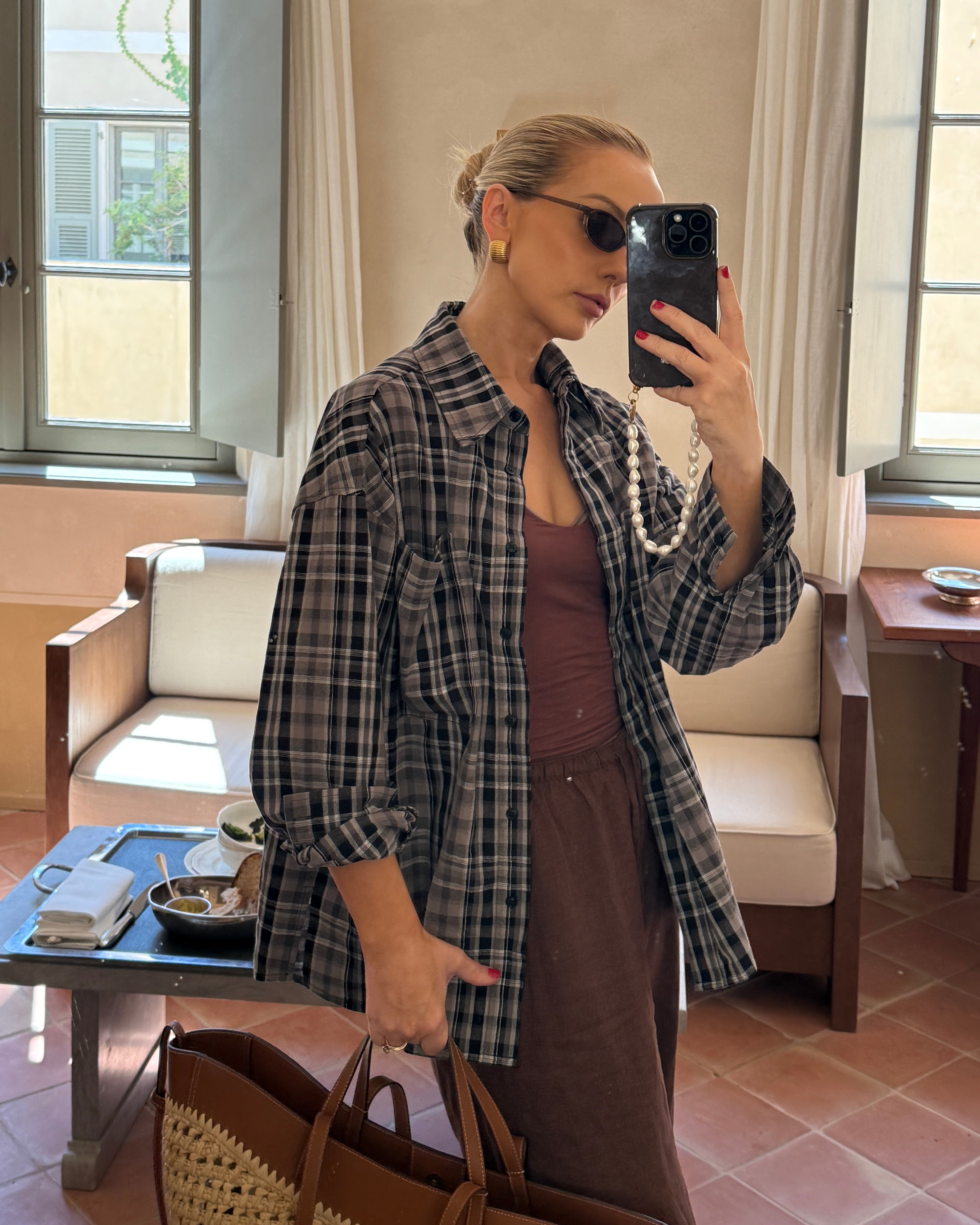 Mirror selfie in a living room, wearing a black and white relaxed plaid shirt and sunglasses