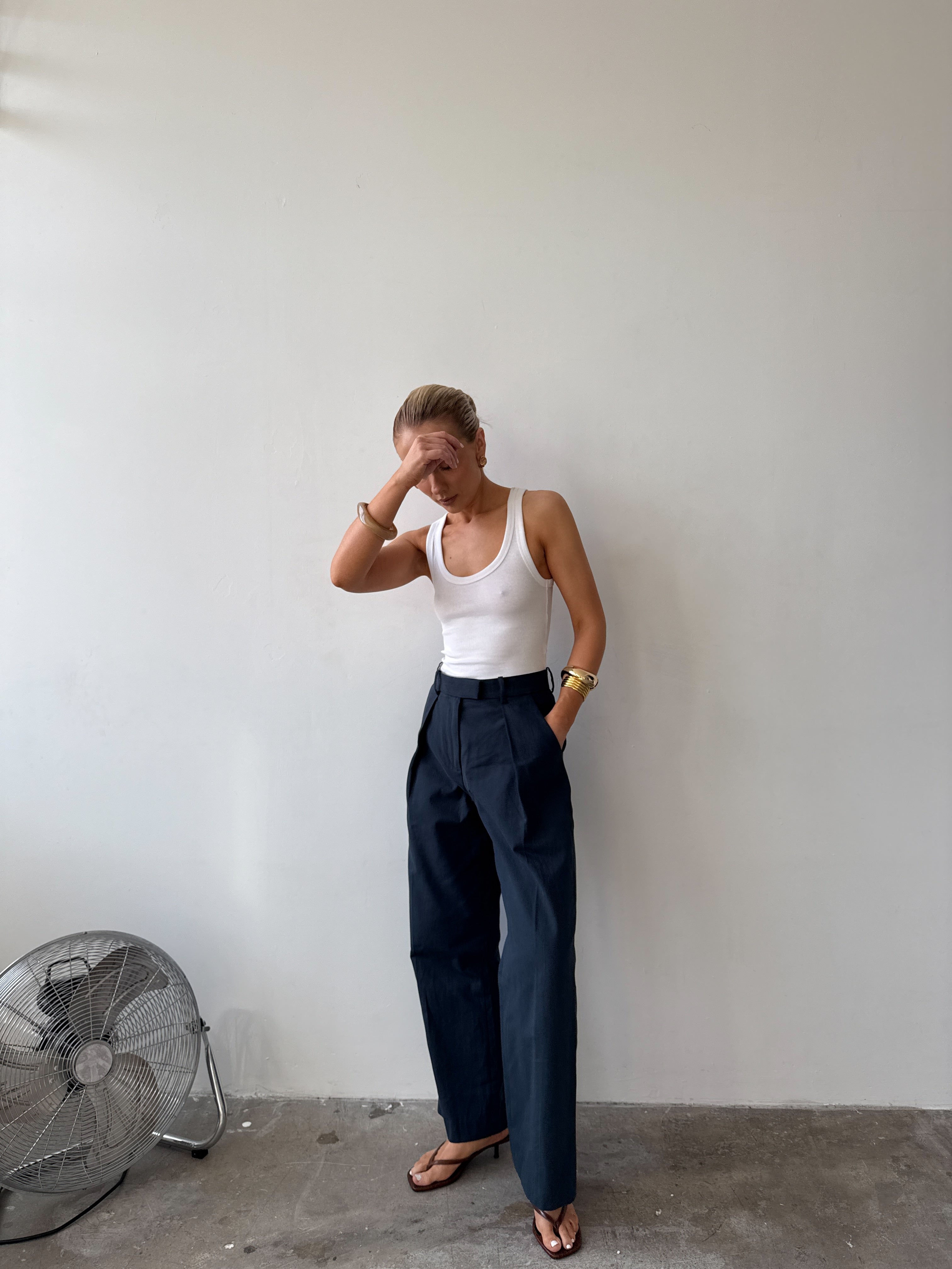 Model wearing a white tank top and ink blue trousers