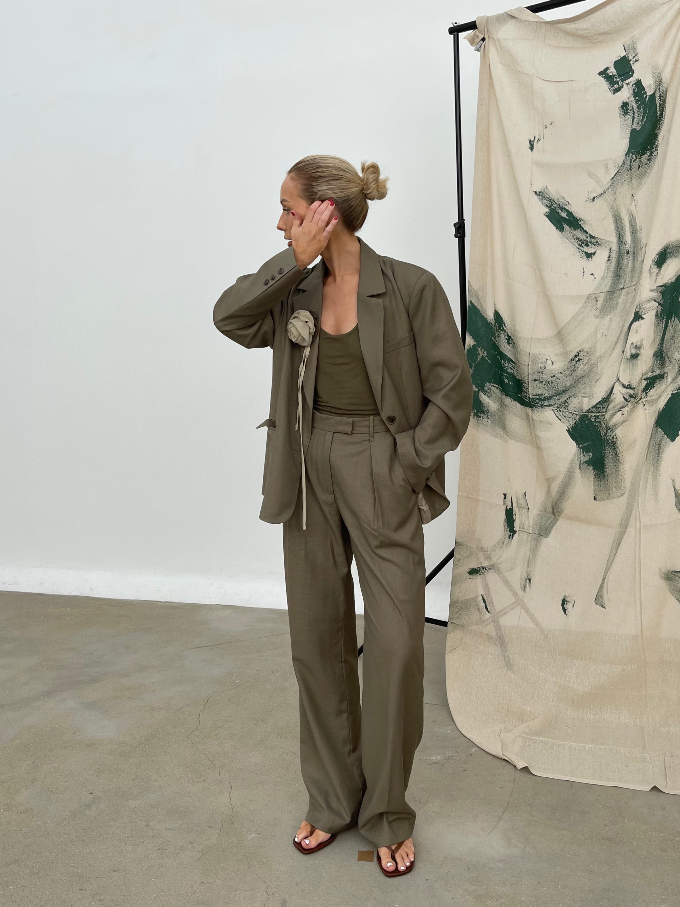 Model in studio wearing an oversized, relaxed fit soft olive Margaux blazer featuring notched lapels paired with matching wide-leg trousers and a tank