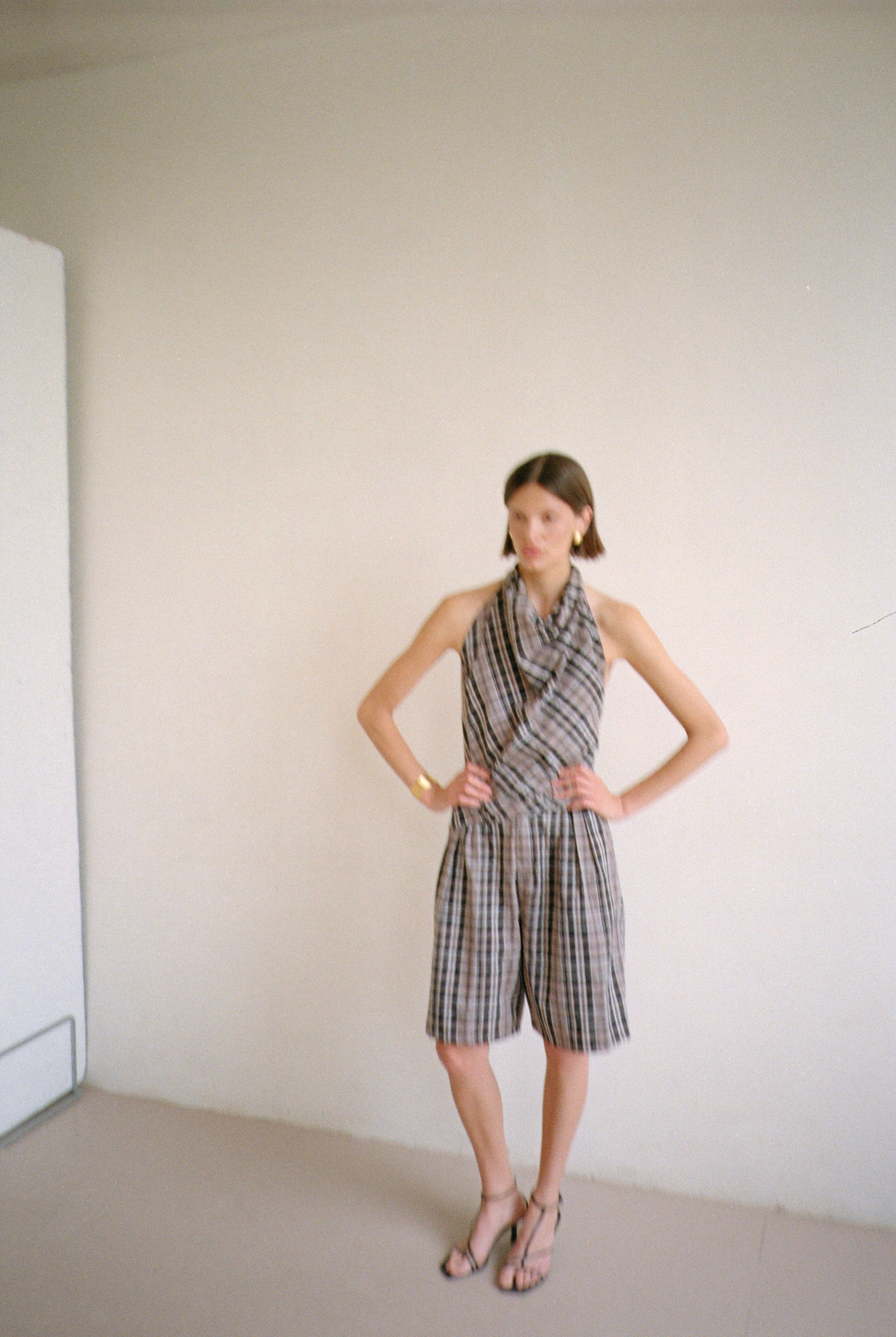 Model wearing checkered halter-style sleeveless top with a draped neckline with matching shorts