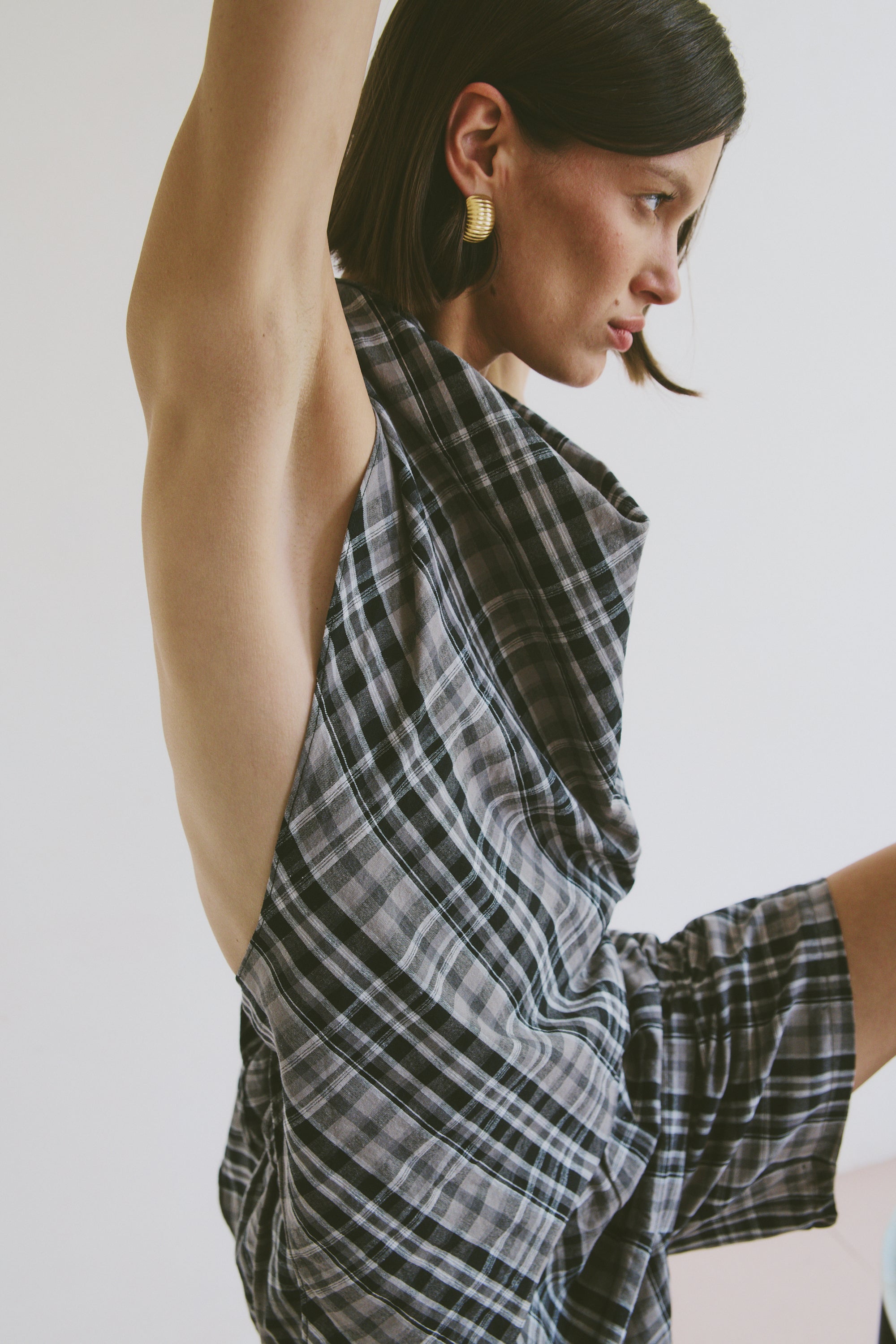 Model wearing a plaid top with matching shorts and gold earrings against a white background