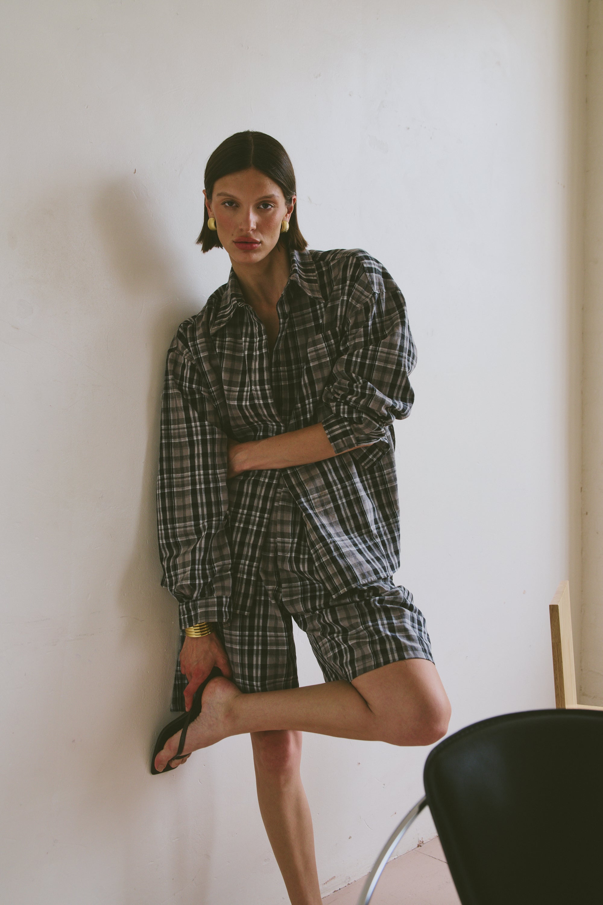 Plaid outfit standing against a white wall