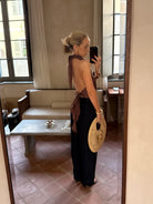 Woman taking a mirror selfie with a phone, wearing a backless top and holding a bag