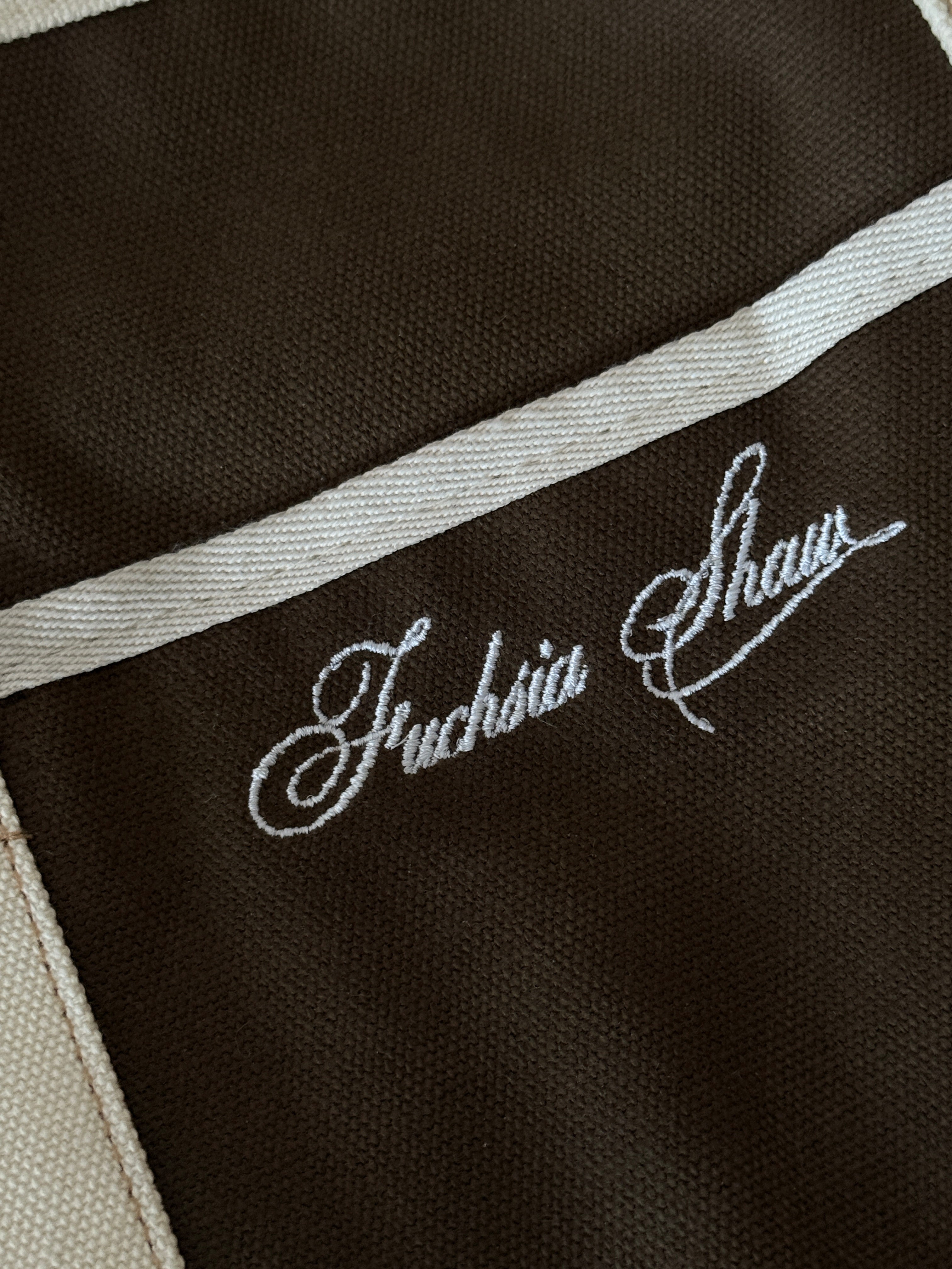 Close up of an embroidered white detail "Fuchsia Shaw"