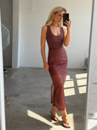 Woman taking a mirror selfie wearing a red-brown top and matching skirt in a minimal room