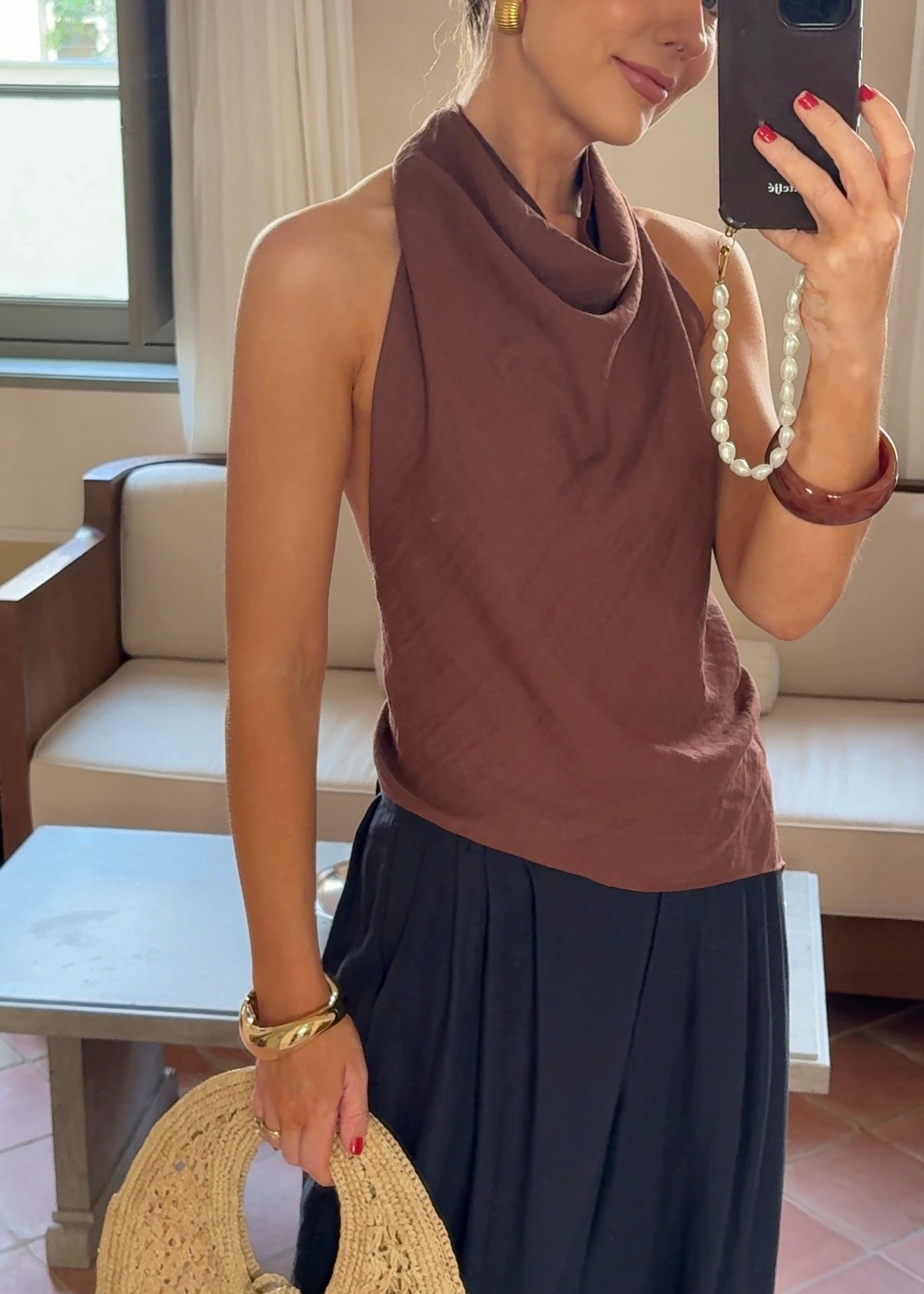 Woman taking a mirror selfie wearing an amber brown top and black skirt in a living room