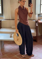 Mirror selfie in an elegant living room, wearing a brown sleeveless asymmetric top and dark blue trousers