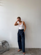 Model wearing a white tank top and ink blue trousers
