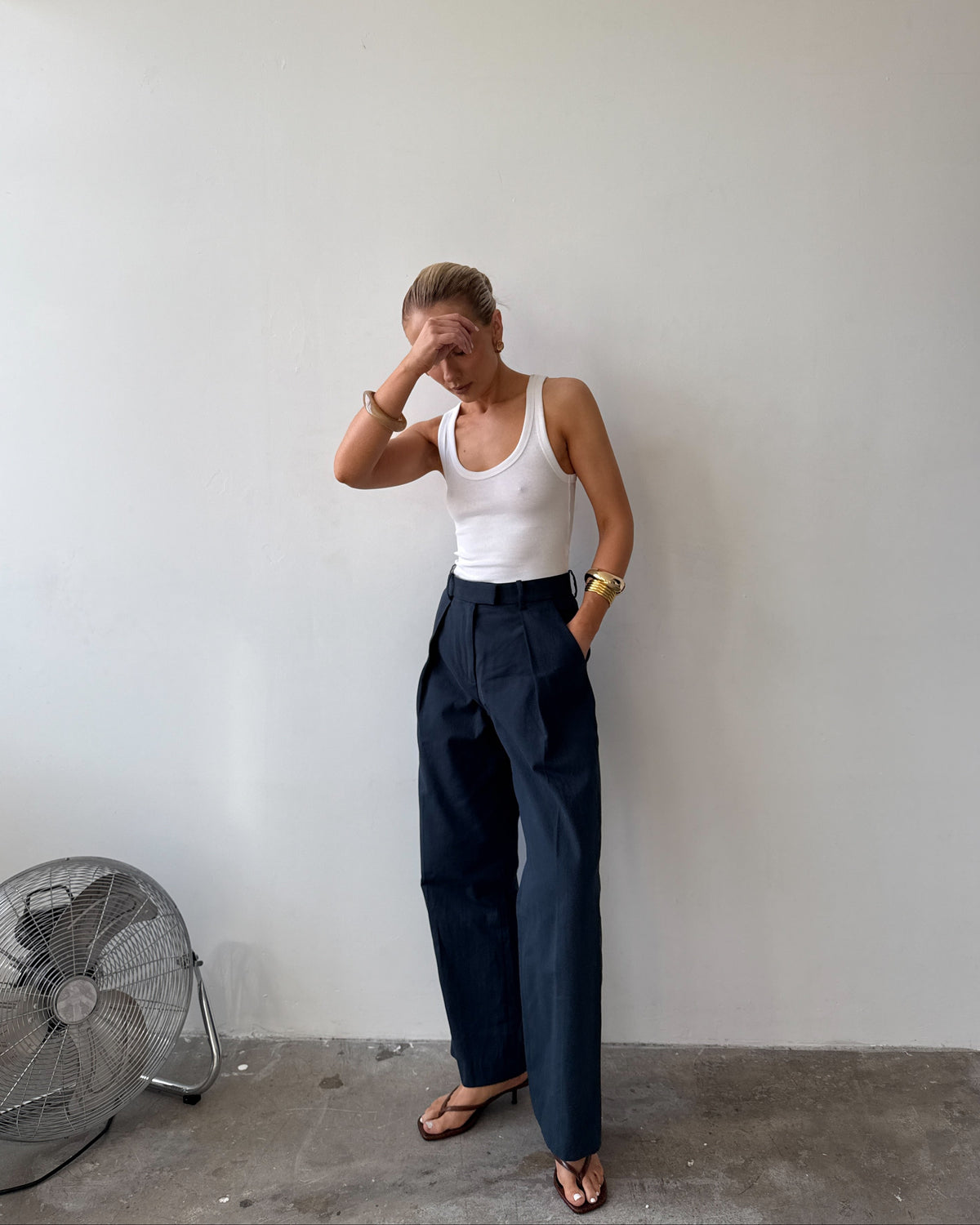 Model wearing a white tank top and ink blue trousers
