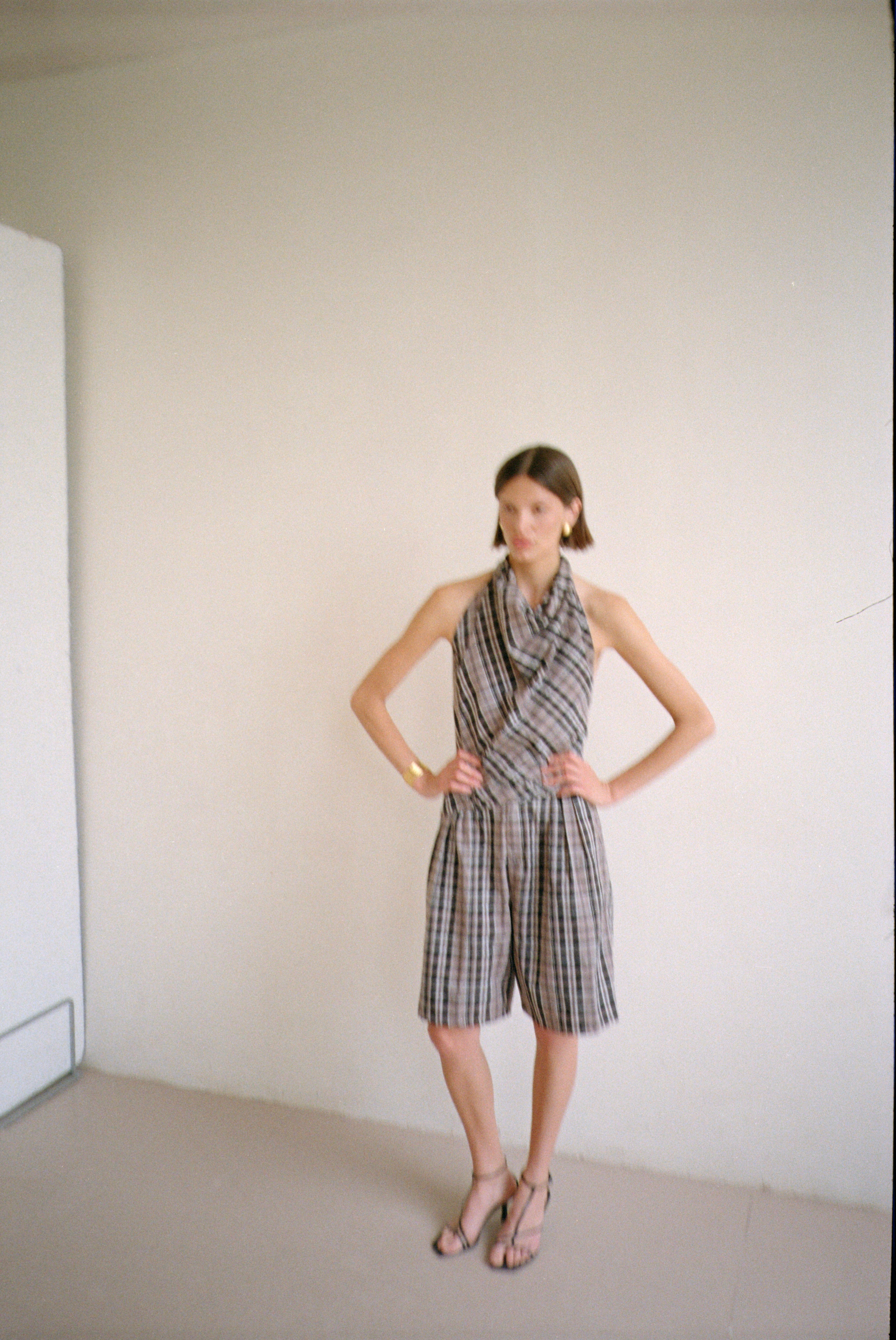 Model wearing checkered halter-style sleeveless top with a draped neckline with matching shorts