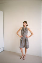 Model wearing checkered halter-style sleeveless top with a draped neckline with matching shorts