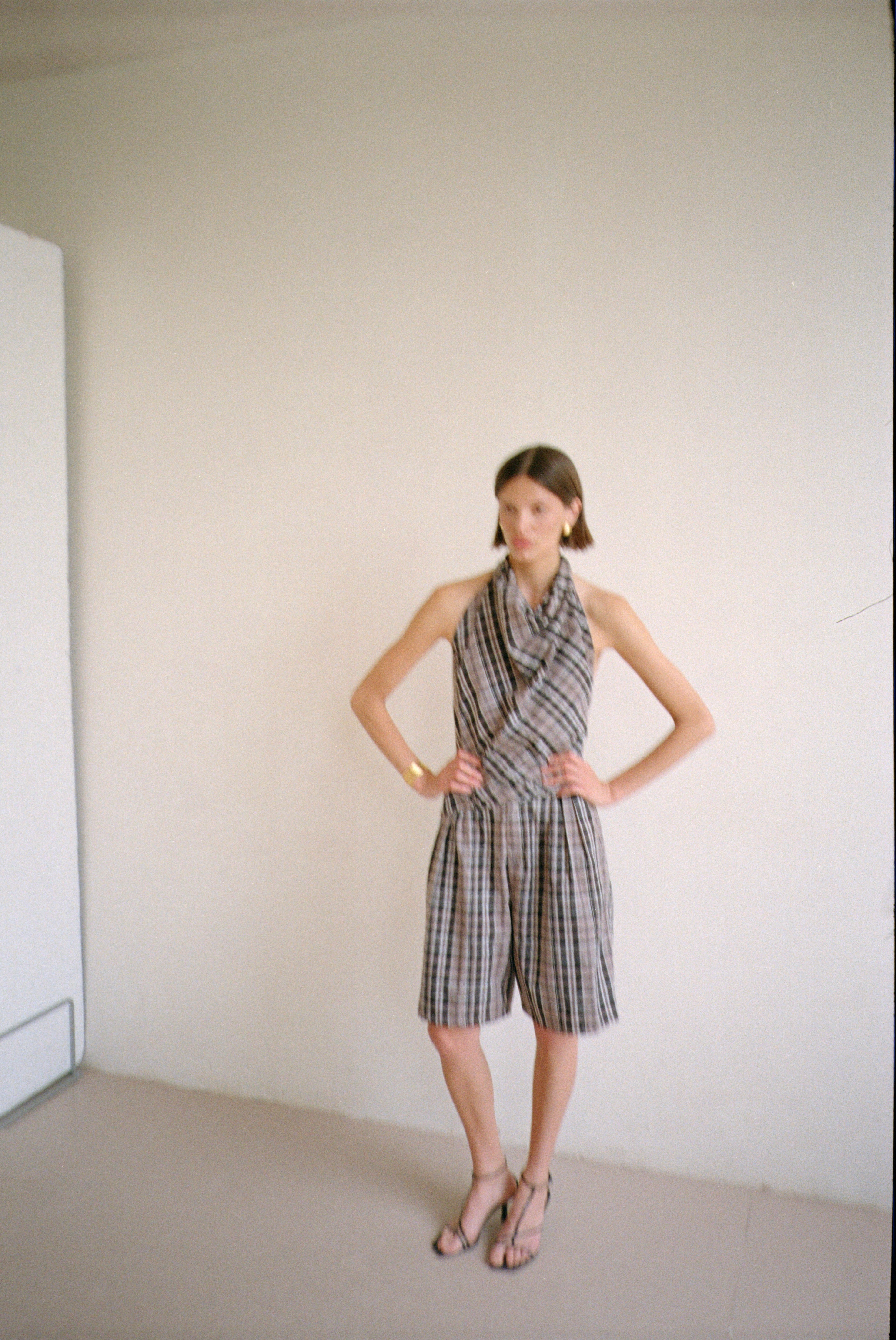 Model wearing checkered halter-style sleeveless top with a draped neckline with matching shorts