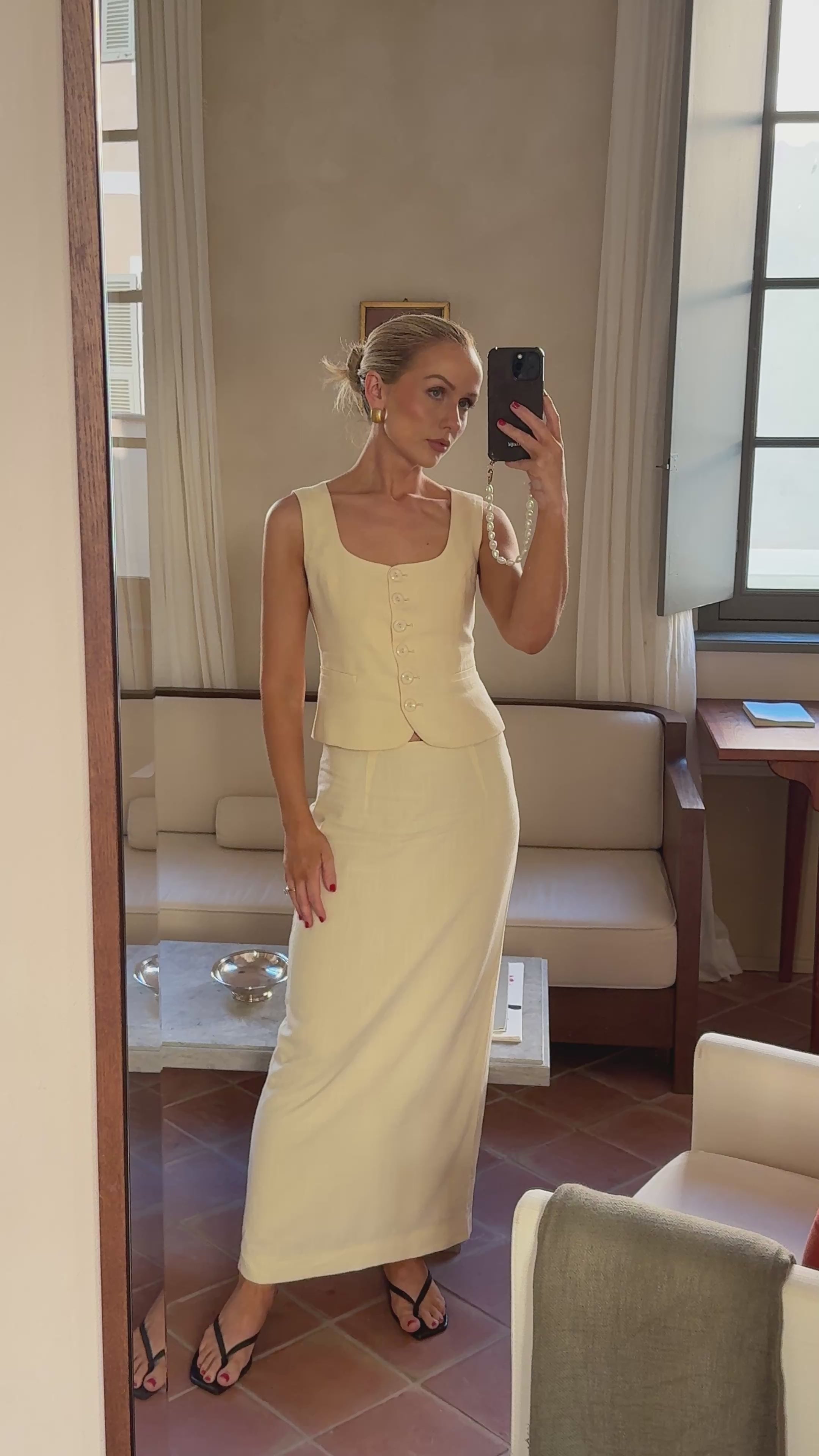 Woman taking a mirror selfie whil wearing a yellow waistcoat and matching skirt