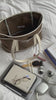 Someone filling a white and brown tote bag with: a jumper, 3 books, hairclip, hairbrush, skincare product, lip gloss, glasses, laptop, planner, tablet, digital camera and a charging cable
