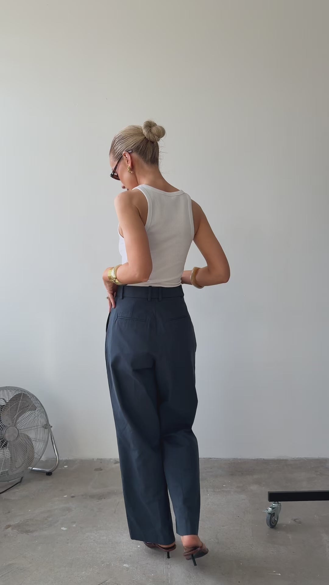 Model wearing blue trousers showing the back and front of her outfit 